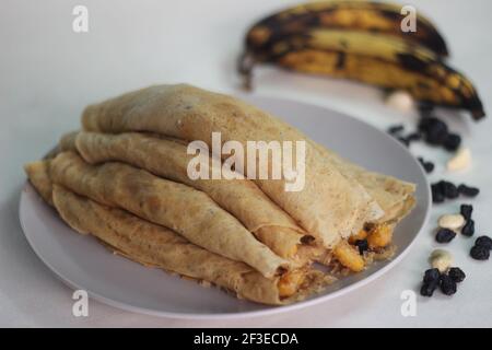 Crêpes ou crêpes plantain faites maison avec mélange de raisins de coco plantain au milieu. Prise de vue sur fond blanc. Banque D'Images