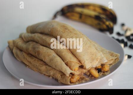 Crêpes ou crêpes plantain faites maison avec mélange de raisins de coco plantain au milieu. Prise de vue sur fond blanc. Banque D'Images