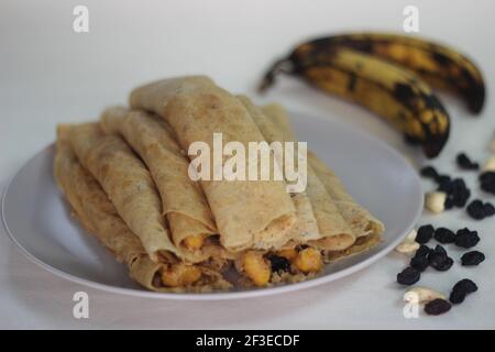 Crêpes ou crêpes plantain faites maison avec mélange de raisins de coco plantain au milieu. Prise de vue sur fond blanc. Banque D'Images