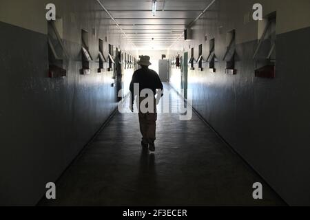 Un ancien prisonnier marche dans les salles de l'ancienne prison sur l'île Robben au large de la côte du Cap, en Afrique du Sud Banque D'Images