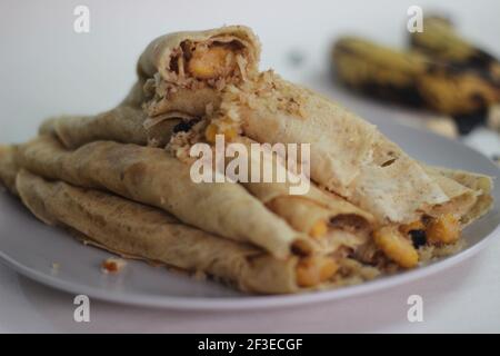 Crêpes ou crêpes plantain faites maison avec mélange de raisins de coco plantain au milieu. Prise de vue sur fond blanc. Banque D'Images