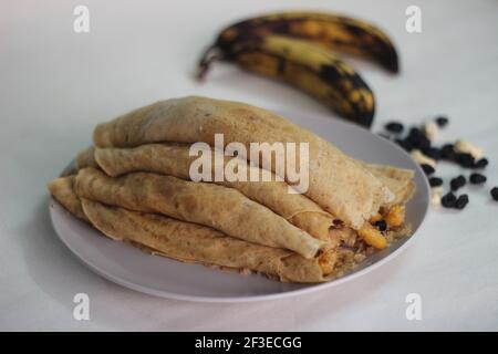 Crêpes ou crêpes plantain faites maison avec mélange de raisins de coco plantain au milieu. Prise de vue sur fond blanc. Banque D'Images