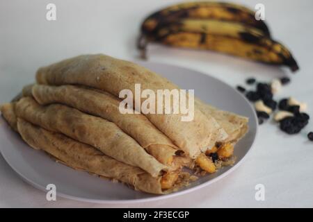 Crêpes ou crêpes plantain faites maison avec mélange de raisins de coco plantain au milieu. Prise de vue sur fond blanc. Banque D'Images