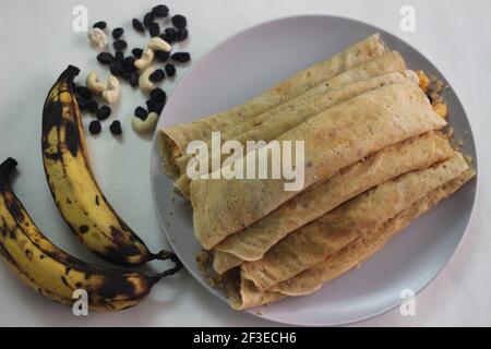 Crêpes ou crêpes plantain faites maison avec mélange de raisins de coco plantain au milieu. Prise de vue sur fond blanc. Banque D'Images