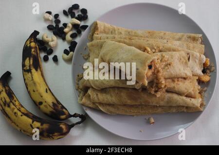 Crêpes ou crêpes plantain faites maison avec mélange de raisins de coco plantain au milieu. Prise de vue sur fond blanc. Banque D'Images