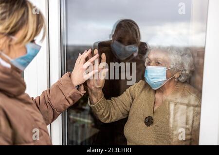 Femme qui visite sa grand-mère en isolement pendant une pandémie de coronavirus Banque D'Images