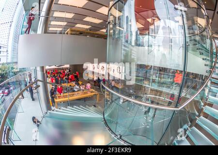 Hong Kong, Chine - 4 décembre 2016 : vue sur le sol à l'œil de poisson du panneau rouge Apple et escalier en colimaçon en verre dans le magasin Apple, IFC Mall, avec Hong Kong Central Banque D'Images