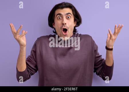 ouah. gai mec gestant avec les mains, montrant la surprise, debout avec la bouche ouverte, isolé sur le violet Banque D'Images