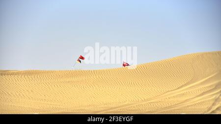 Une belle vue des drapeaux sur les poteaux qui agite dans le désert d'Al Qudra contre un ciel bleu Dubaï, Émirats arabes Unis Banque D'Images