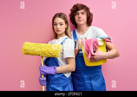 Concept d'entretien ménager. Assurance mari et femme avec des fournitures de nettoyage dans les mains commencer le nettoyage dans la maison, prêt à faire des tâches domestiques. isola Banque D'Images