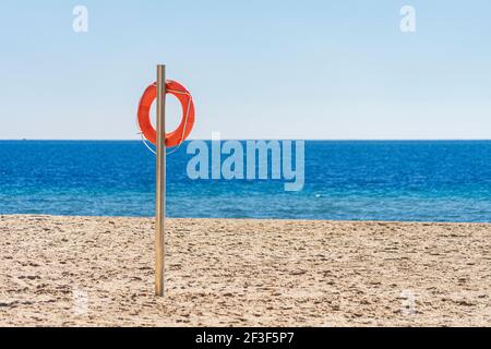 Bouée de sauvetage orange sur une plage de sable vide en face de la mer Méditerranée. Bouée de sauvetage, ceinture de sauvetage sur le poteau Banque D'Images