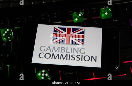 Viersen, Allemagne - 1er mars. 2021: Gros plan de smartphone avec le logo lettrage de la uk Gaming commission autorité de licence sur le clavier d'ordinateur Banque D'Images