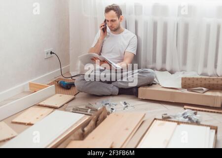 Un client homme appelle pour aider le centre à la maison lors de l'assemblage de nouveaux meubles, appelant pour un maître. Banque D'Images