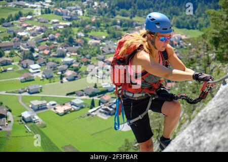 La femme monte via la voie ferrata Nassereith au-dessus du village de Dormitz, en Autriche. Été, aventure, tourisme. Banque D'Images