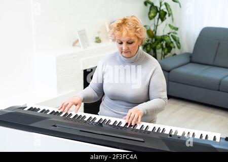 Senior woman in retraite active living joue du piano dans sa maison. Banque D'Images