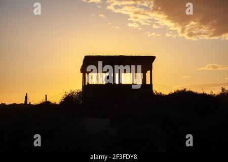 Silhouette de l'homme dans la tour de l'observatoire des oiseaux au coucher du soleil Rétroéclairage du ciel Las Salinas de Cabo de Gata Banque D'Images