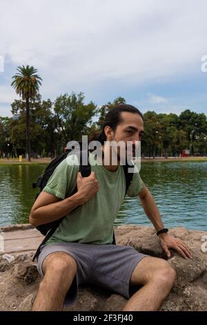 mâle explorateur regardant la forêt sur un rocher surplombant la rivière. homme grimpeur. moment de détente et de dispersion. Banque D'Images