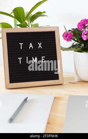 Tableau de lettres en feutre noir, ordinateur portable, bloc-notes et pots de fleurs sur la table. Concept de déclaration de revenus des entreprises. Banque D'Images