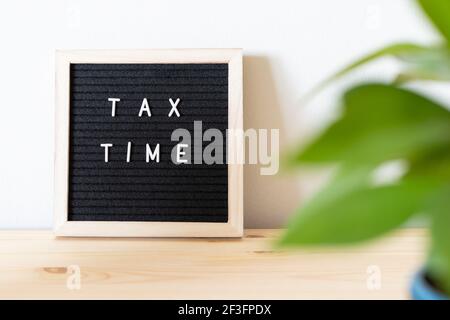 Tableau de lettres en feutre noir et pot de fleurs sur la table pour l'heure d'imposition. Concept de déclaration de revenus des entreprises. Banque D'Images