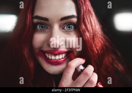 Portrait de l'adolescence folle-regardant avec des cheveux rouges elle est rouge rouge rouge rouge rouge sur son visage, horreur concept. halloween temps. Peur et cauchemar Banque D'Images