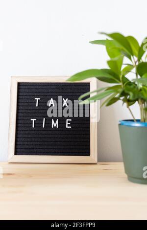 Tableau de lettres en feutre noir et pot de fleurs sur la table pour l'heure d'imposition. Concept de déclaration de revenus des entreprises. Banque D'Images