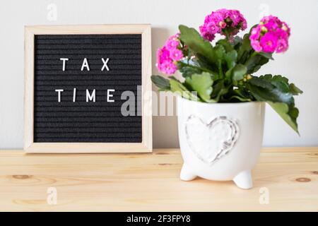 Tableau de lettres et pots de fleurs en feutre noir pour l'heure d'imposition sur la table. Concept de déclaration de revenus des entreprises. Banque D'Images