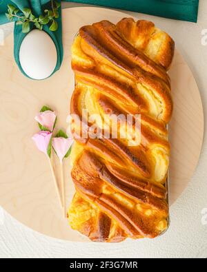 Gâteau de levure cuit avec du fromage à la crème, et des œufs blancs gros plan sur une planche de service en bois, plat, bannière verticale. Brioche et œufs. Printemps, Banque D'Images