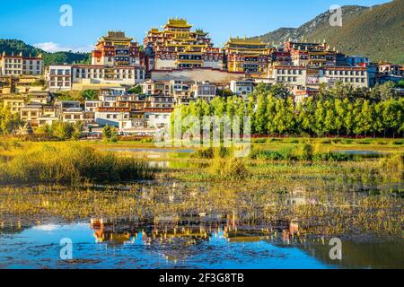 Magnifique vue panoramique sur le monastère de Songzanlin avec reflet de l'eau à Coucher de soleil et lumière spectaculaire à Shangri-la Yunnan Chine Banque D'Images