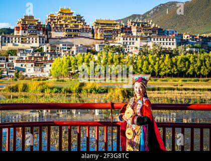 Shangila Chine , 8 octobre 2020 : femme en robe traditionnelle posant devant le monastère de Songzanlin au coucher du soleil à Shangri-la Yunnan en Chine Banque D'Images