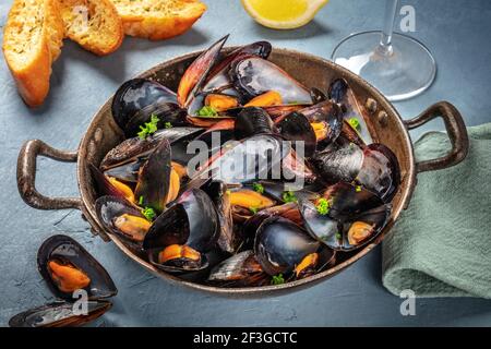 Moules fraîches dans une casserole, avec persil et citron Banque D'Images