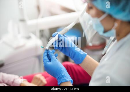 Chirurgien dentaire mettant sur le gobelet Prophy sur le foret dentaire Banque D'Images