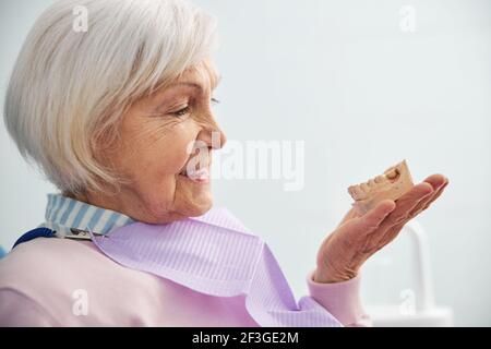 Pensioner tenant les dents inférieures coulées à la main Banque D'Images
