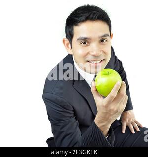 Jeune homme d'affaires tenant une pomme verte avec un visage souriant Banque D'Images