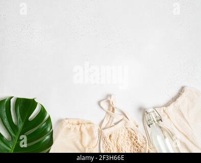 Divers sacs avec cordon, sac à ficelle sac écologique en tissu de coton naturel et bouteille de verre plat posé sur fond gris clair. Vue de dessus. Banque D'Images