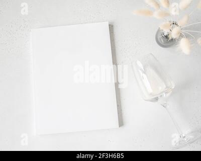 Maquette de la couverture du magazine blanc, lagurus blanc dans un vase et vin blanc en verre sur fond gris clair. Vue du dessus. Copier l'espace Banque D'Images