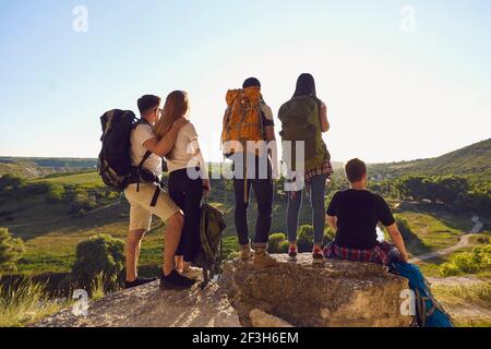 Groupe de touristes randonneurs debout et assis et appréciant le vert paysage de vallée sur les vacances d'été Banque D'Images