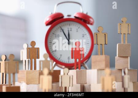 Figurines en bois avec un support rouge à côté de l'alarme horloge Banque D'Images