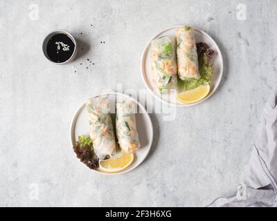 Rouleaux de printemps vietnamiens avec salade, sauce, crabe et nouilles sur les assiettes et saules dans un bol sur fond gris. Vue du dessus. Espace pour les copies Banque D'Images
