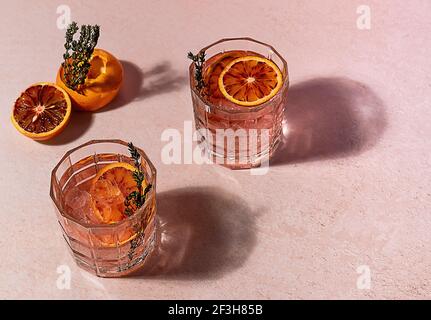 Cocktail de gin rose avec du sang rouge orange et de la glace par beau temps. Des reflets durs tendance. Banque D'Images