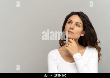 Pensive woman concentrated and ponders, thinking over sale offer making choice, looking aside Stock Photo