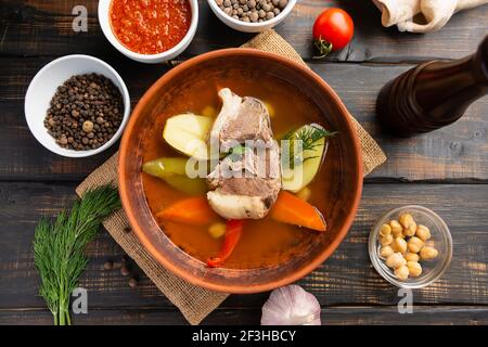 Soupe Shurpa de cuisine orientale ouzbek. Avec bœuf ou agneau et légumes, dans un bol en argile sur fond de bois sombre. Banque D'Images