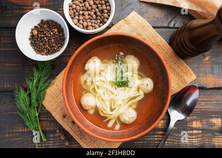 Soupe de nouilles aux boulettes de viande avec persil et aneth à l'obscurité arrière-plan en bois Banque D'Images