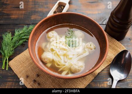 Soupe de nouilles aux boulettes de viande avec persil et aneth à l'obscurité arrière-plan en bois Banque D'Images