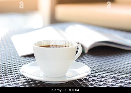 Tasse à café avec livre sur table en osier brun Banque D'Images