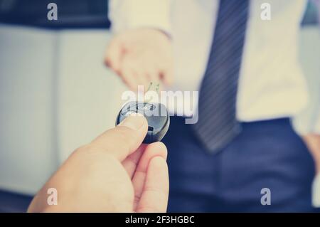 Remise à la main de la clé de la voiture à un homme d'affaires, vente de voiture et concepts de location - style rétro Banque D'Images