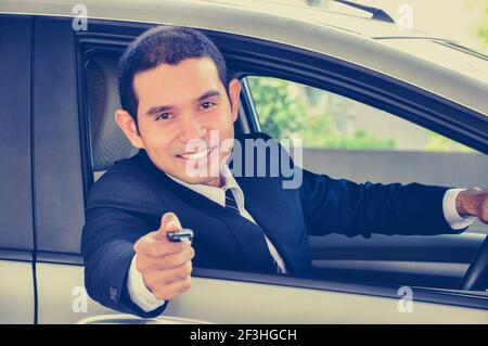 Homme d'affaires souriant donnant une clé de voiture - style vintage (rétro) effet de couleur Banque D'Images
