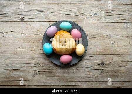 petit pain de pâques pinze avec quelques œufs de pâques colorés arrière-plan en bois Banque D'Images