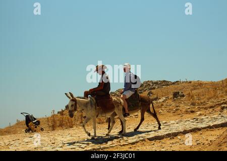 RHODES, GRÈCE - 06 juillet 2018: Plan horizontal de deux hommes en chapeaux à cheval sur les ânes dans la zone rurale de Rhodes, Grèce Banque D'Images