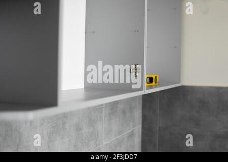 Détails des armoires de cuisine personnalisées. Cuisine modulaire grise en carton sur une variété d'étapes d'installation dans la cuisine avec un carrelage gris Banque D'Images