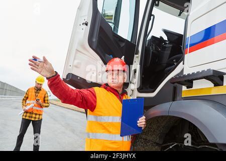 Le directeur de la construction sur camion avec liste de contrôle donne des directives pour la construction travailleurs sur le chantier Banque D'Images